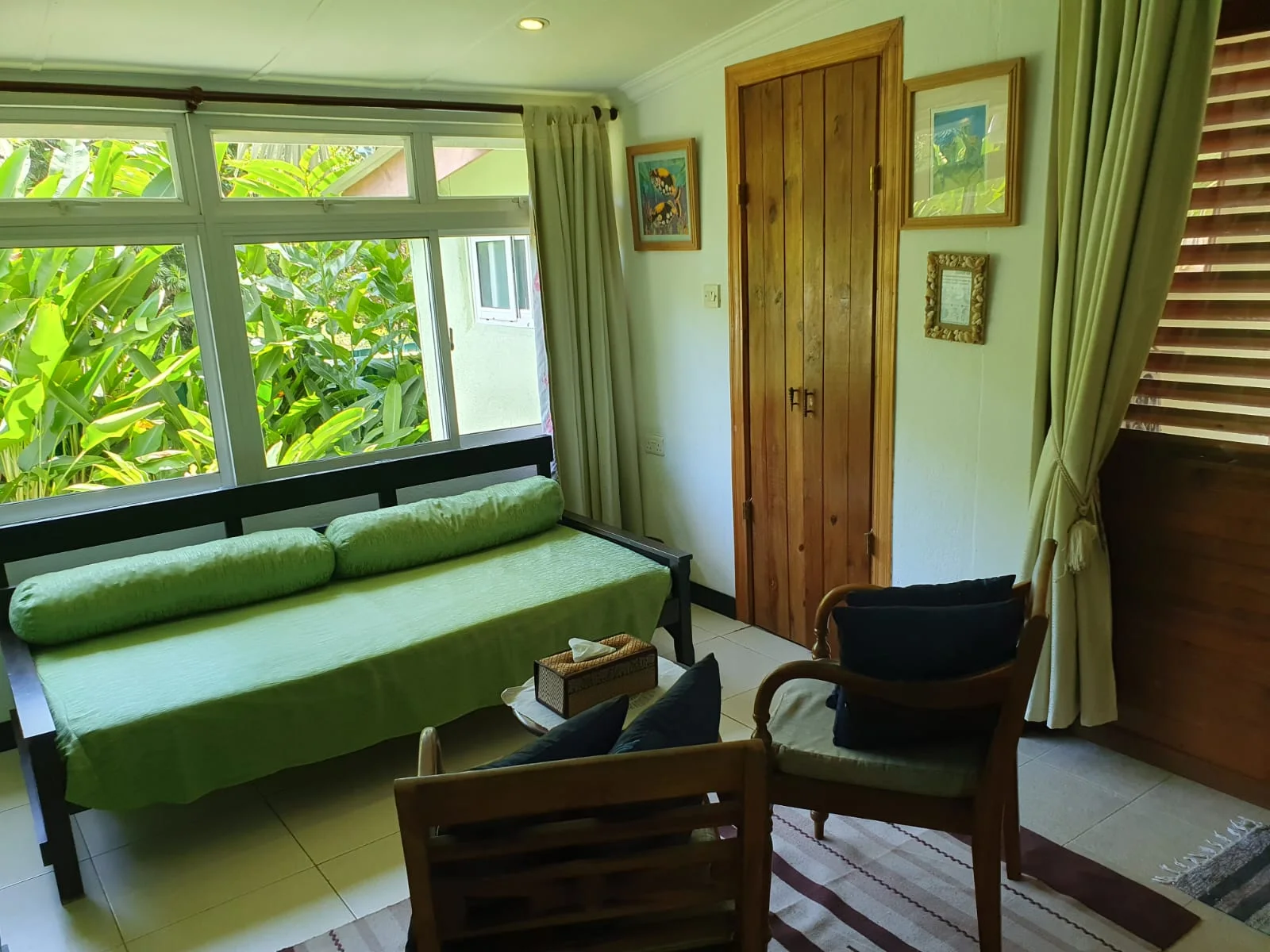 Garden Suite 3 living area with lime-green daybed, wooden armchairs and large windows overlooking tropical foliage — Cinnamon self-catering suite at Maison Soleil at Maison Soleil, Anse Soleil, Seychelles (indoor-outdoor living, Anse Soleil)